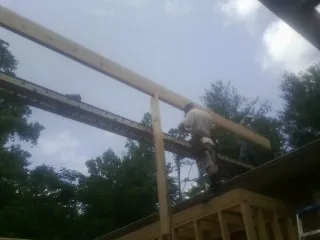 Carpenter setting a ridge beam over a new addition frame — Ice Dam Removal by Roofing Brothers in Reydon