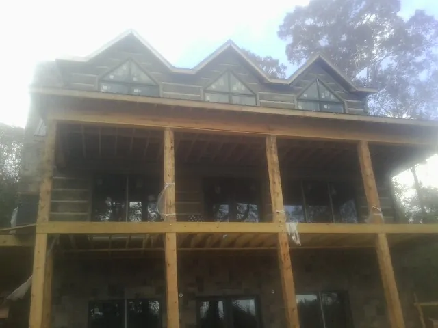 Dormers and porch framing on a large log home under construction — Roof Coating work by our crew in Reydon