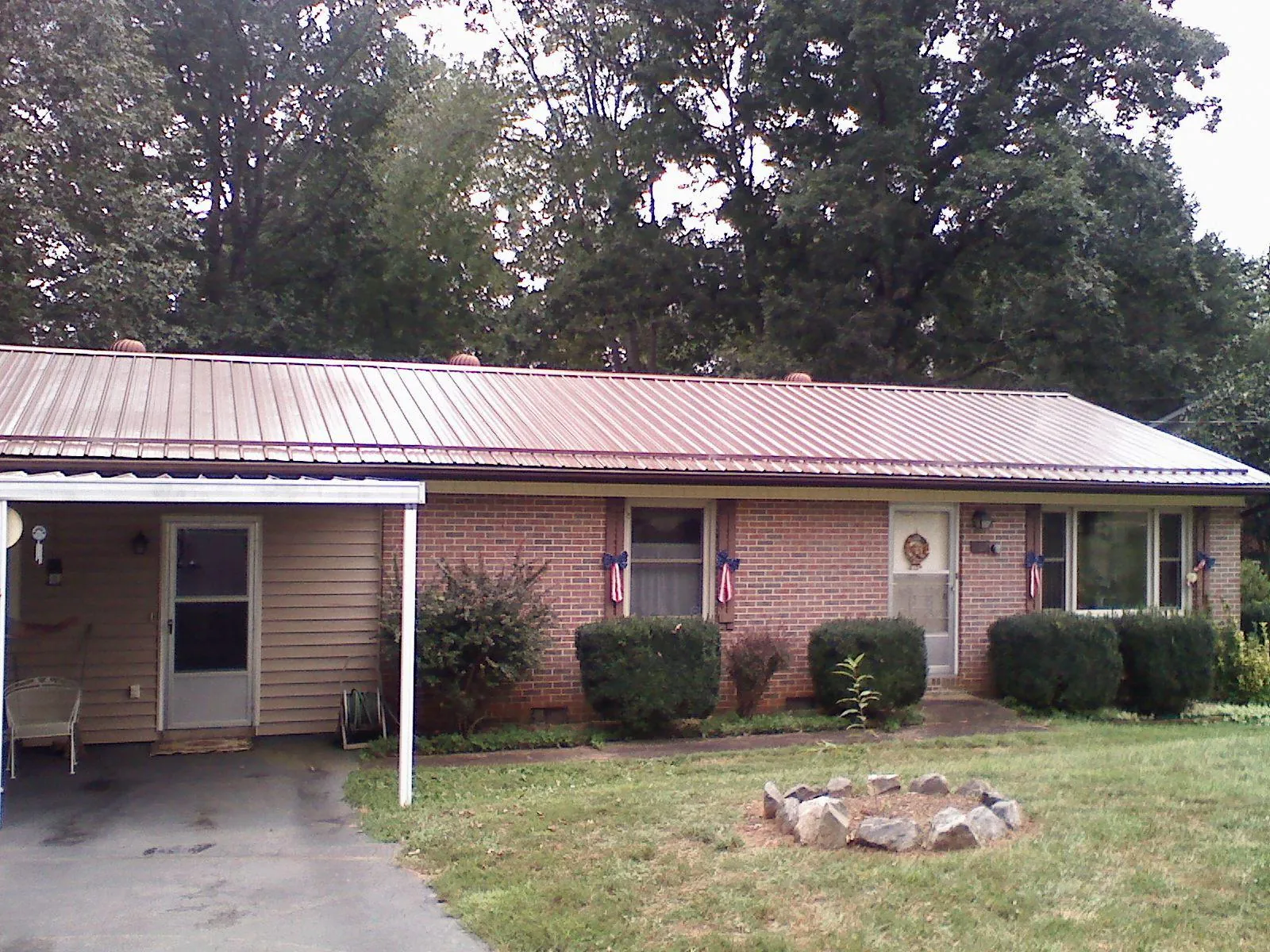 Bronze metal roof and carport on a brick ranch home — Roof Repair work by our crew in Reydon